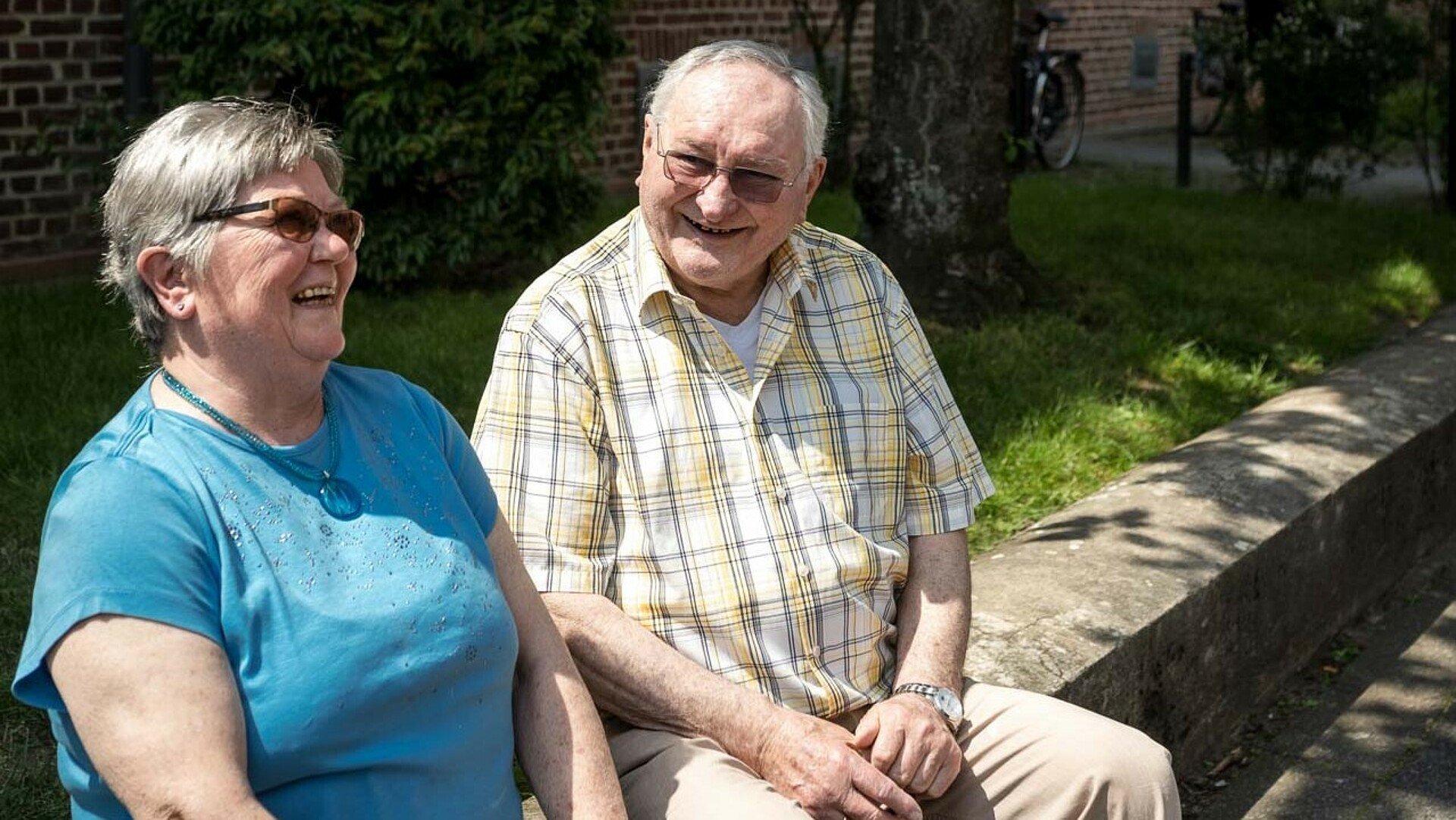 Ehepaar Neubert sitzt lachend in einem Vorgarten der Germaniasiedlung in Höhenberg